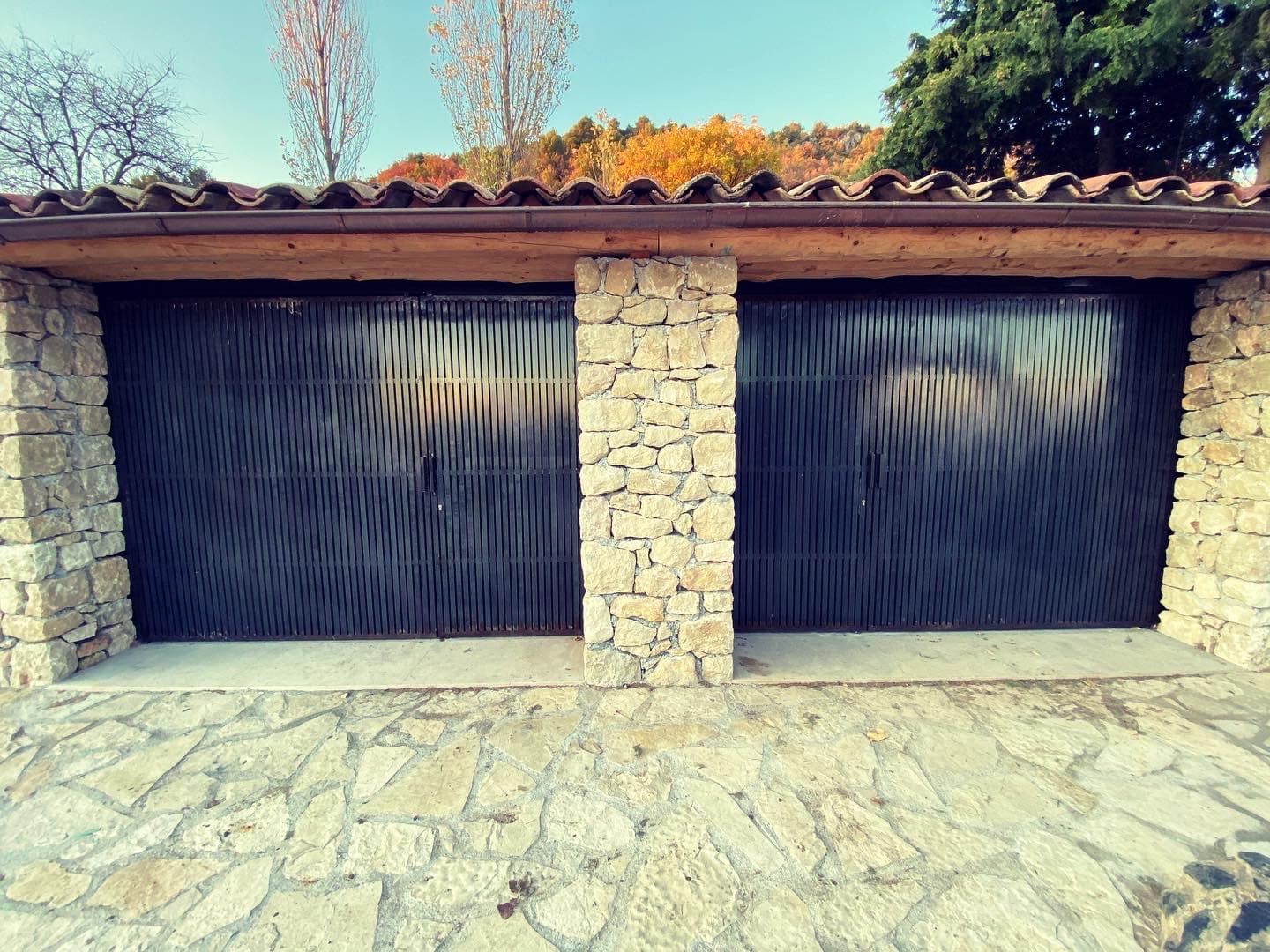 Deux portes de garage sombres séparées par un pilier en pierre