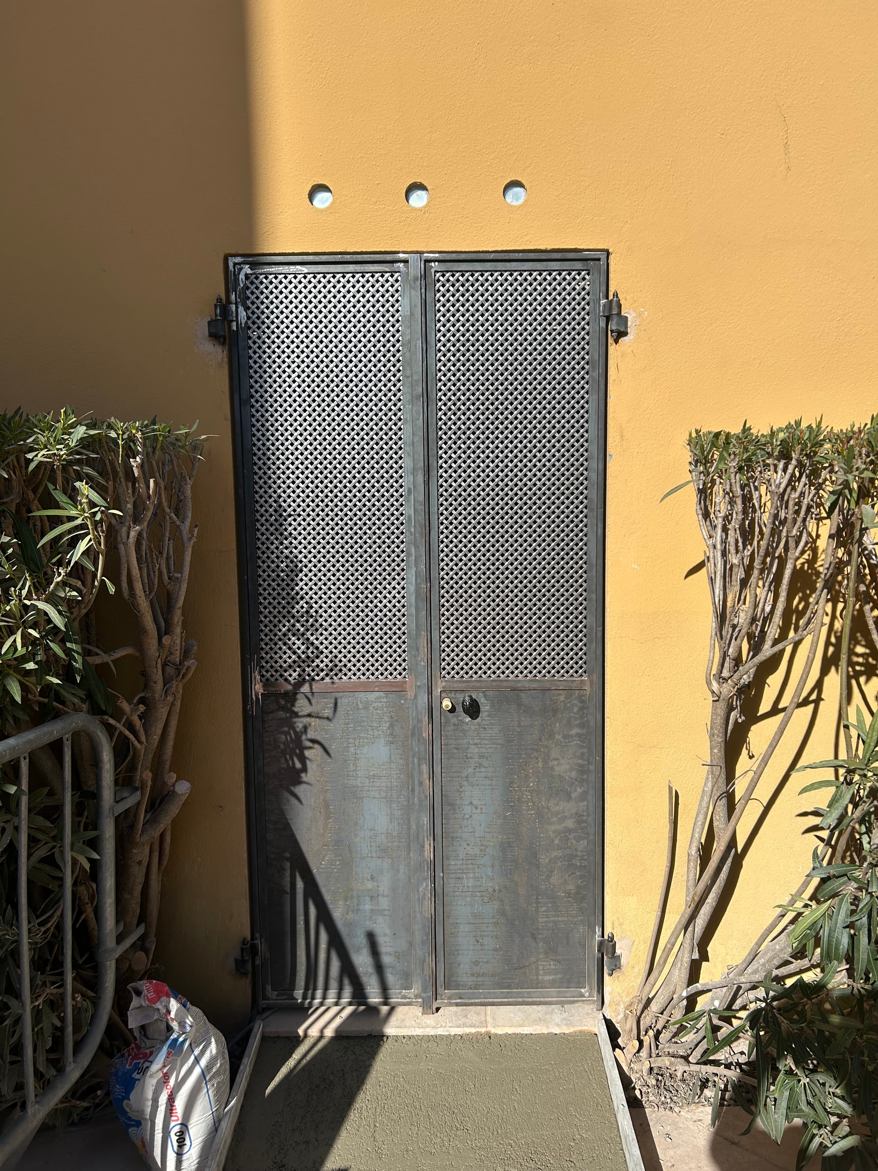Porte métallique ajourée dans une façade ocre