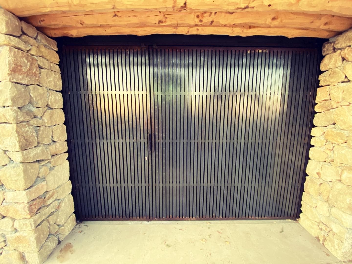 Porte de garage à lames verticales dans un encadrement en pierre